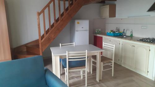 eine Küche mit einem Tisch und Stühlen sowie eine Treppe in der Unterkunft Casa Arborea in Marrùbiu
