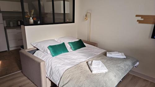 a bed with two green pillows on it in a room at Le gîte de Varanges in Givry
