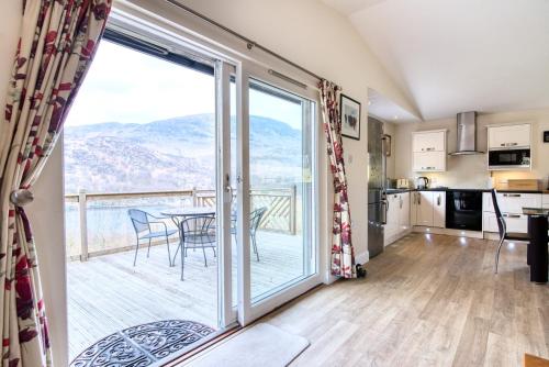 une cuisine et une salle à manger avec une grande porte coulissante en verre. dans l'établissement Kingfisher Lodge sleeps up to 4, à Crianlarich