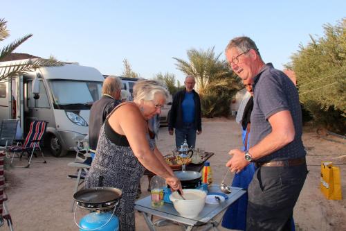a man and a woman preparing food at a table at Camping , Maison d'hôte Bivouac hyatt-tata in Tatta