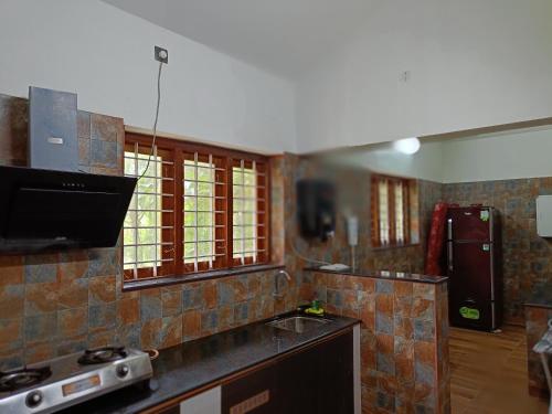 a kitchen with a stove and a counter top at Anandam Stays - Premium 3BHK plush homestay, Vaikom near Kumarakom in Vaikom