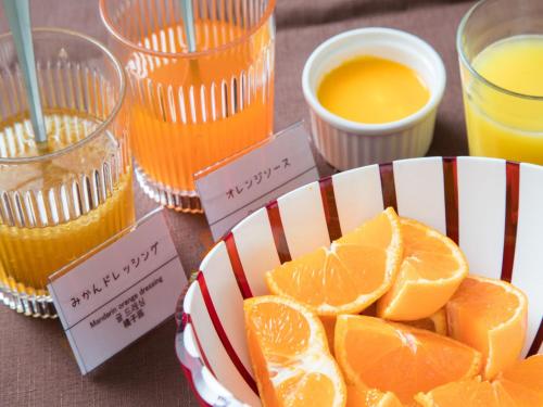 a plate of orange slices on a table with drinks at Dormy Inn Matsuyama Natural Hot Spring in Matsuyama
