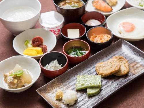 a table with a plate of food and bowls of food at Dormy Inn Matsuyama Natural Hot Spring in Matsuyama