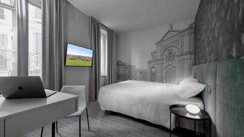Schlafzimmer mit einem Bett und einem Laptop auf einem Schreibtisch in der Unterkunft Be Duomo - Self Check-in in Voghera