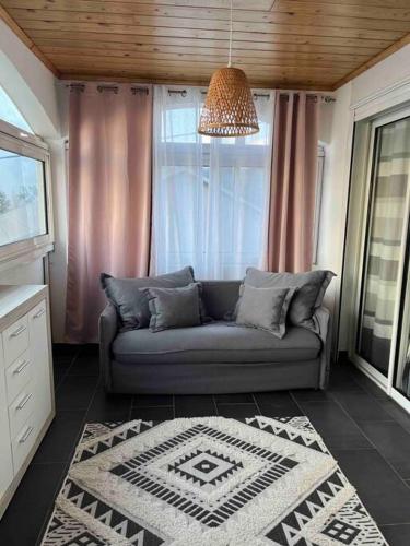 a living room with a couch and a window at Villa Bois Court 3 chambres in Le Tampon