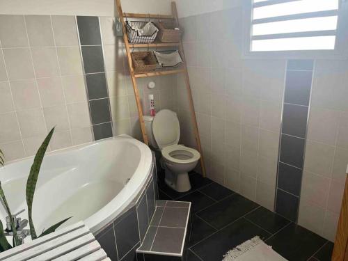 a bathroom with a bath tub and a toilet at Villa Bois Court 3 chambres in Le Tampon