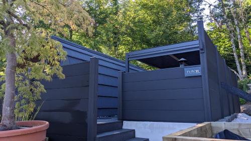 a black house with a black gate and stairs at Beach House Pods in Dunoon