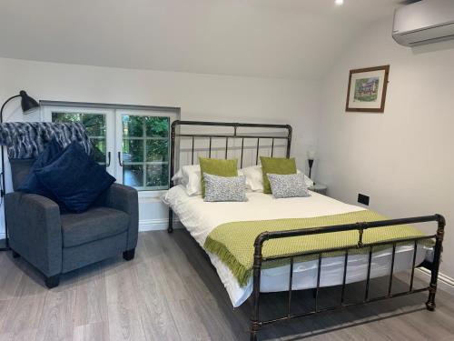 a bedroom with a bed and a chair and a window at Robin's Nest - a self contained detached annex with sky sports & movies in Newborough