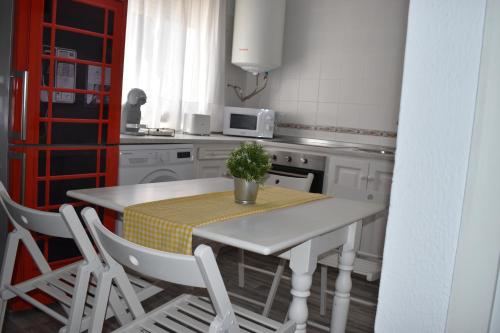 a white kitchen with a table and chairs and a microwave at Apartamento Puertomar in El Puerto de Santa María