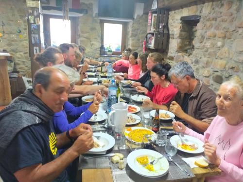 un grupo de personas sentadas en una mesa larga comiendo comida en Albergue el Castillo en Villafranca del Bierzo