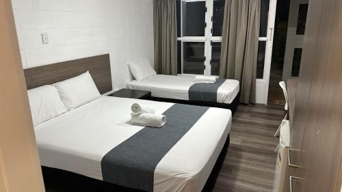 a hotel room with two beds and a towel at Townsville City Motel in Townsville