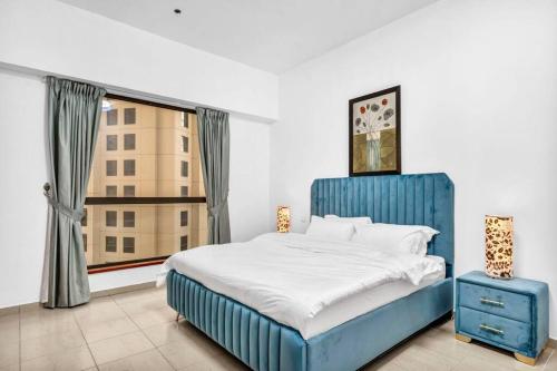 a blue bed in a room with a window at Modern 3BR Flat in the Heart of Dubai JBR in Dubai
