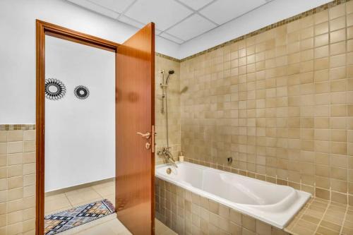 baño con bañera y puerta de cristal en Modern 3BR Flat in the Heart of Dubai JBR en Dubái