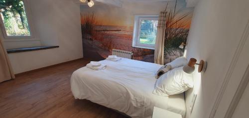 a bedroom with a white bed with a painting on the wall at Le Domaine de la Férière in Sallen