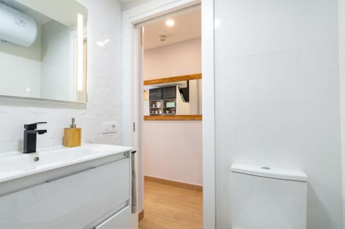 a white bathroom with a sink and a mirror at OASIS PLAYA DEL INGLES 324 by Homestaygrancanaria in San Bartolomé de Tirajana