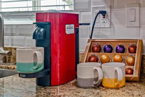 een rood koffiezetapparaat naast twee kopjes en een doos muffins bij Gorgeous 4-bed home with Golf, Pool, & Hot Tub! in Phoenix