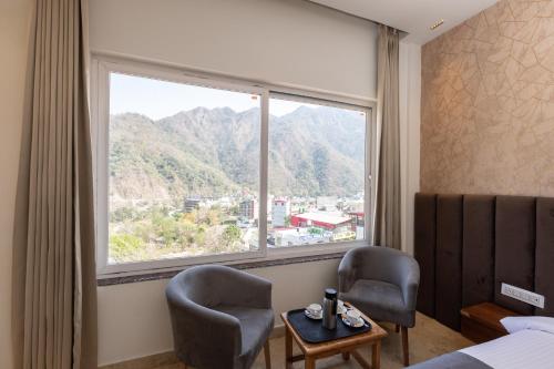 a hotel room with two chairs and a window at Vyom Boutique Hotel Rishikesh in Rishīkesh
