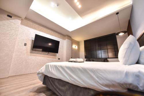 a bedroom with a large bed and a flat screen tv at Two Couples Leisure Art Motel in Tainan