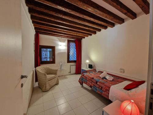 a bedroom with a bed and a chair in a room at Veneziacentopercento Rooms in Venice