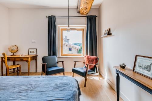 a bedroom with a bed and a desk and a window at Maison de Pagneux in Lachassagne