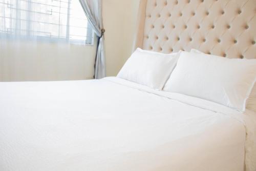 a white bed with white pillows and a window at Vitasolo Hometel & Suite in Tagum