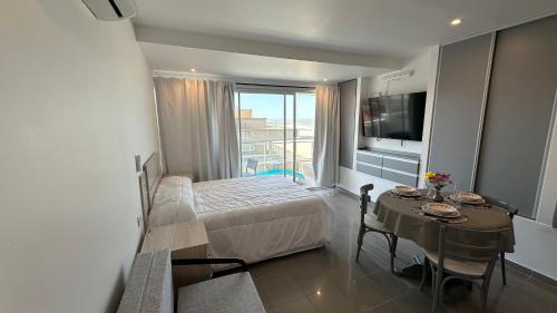 1 dormitorio con cama, mesa y balcón en 5 Soles II en Pinamar