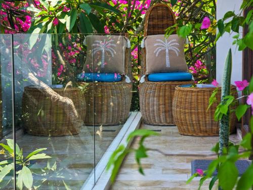 a patio with wicker chairs and pink flowers at Indi Villas - The Bhadra Villa in Seminyak