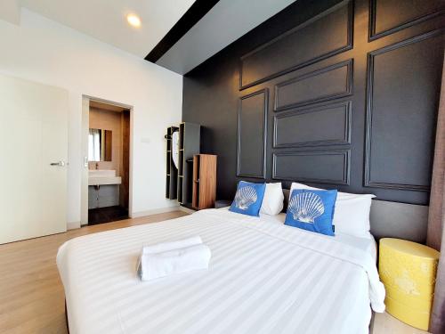 a bedroom with a large white bed with blue pillows at Arte Plus By Sleepy Bear in Batu Empat