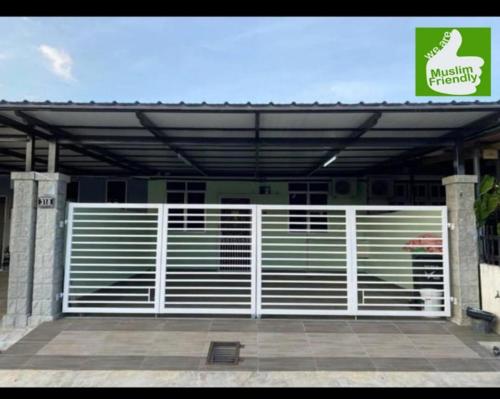 a garage with a white gate in front of a building at Sri Aman Homestay in Jitra