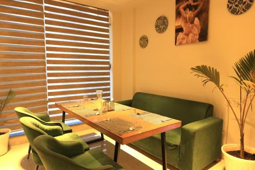 a dining room with a table and green chairs at Vyom Boutique Hotel Rishikesh in Rishīkesh