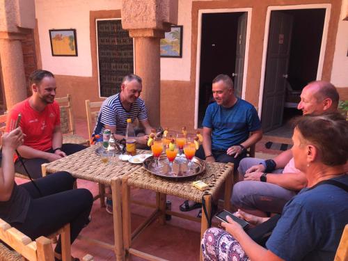 a group of men sitting around a table with drinks at Riad Nkob in Nkob