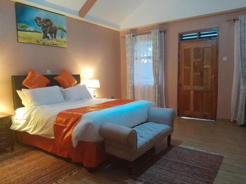 una camera con un letto, una sedia e una porta di PENETY AMBOSELI RESORT ad Amboseli