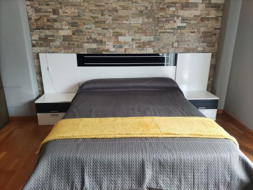 a bed in a room with a brick wall at Jardines de Viana in Viana