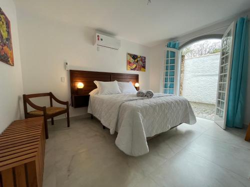 a bedroom with a bed and a chair and a window at Casa Arte Cabore in Paraty