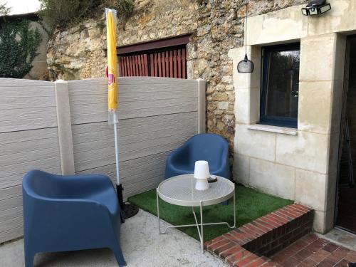 un patio avec deux chaises, une table et un parasol dans l'établissement La cav ô lauriers, à Lunay