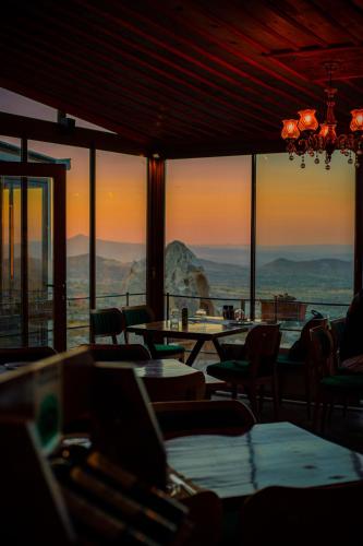a restaurant with tables and chairs and a view of the mountains at Caldera Cave Hotel in Uchisar