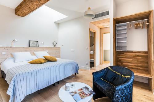 a bedroom with a bed and a chair and a table at Maison de Pagneux in Lachassagne