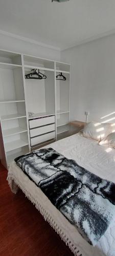 - une chambre avec un lit et une couverture noire et blanche dans l'établissement Apartamento Ortuella, à Ortuella