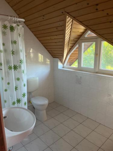 een badkamer met een bad, een toilet en een raam bij Z&T Apartmanok in Siófok