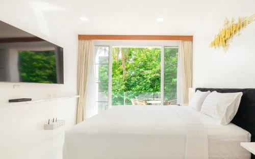 um quarto com uma cama branca e uma janela em Rudi Condo by Q Conzept em Praia de Kata