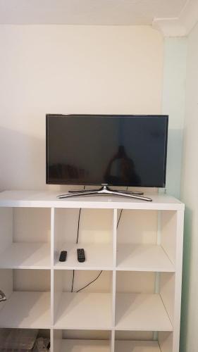 a white entertainment center with a flat screen tv on it at Double bedroom in Raynes Park in London