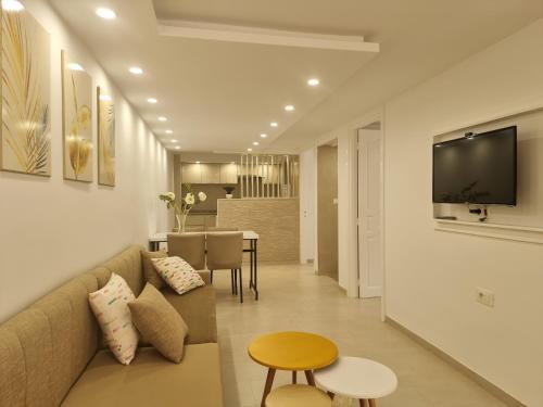 uma sala de estar com um sofá e uma televisão na parede em Appartement de luxe près de la mer em Nabeul
