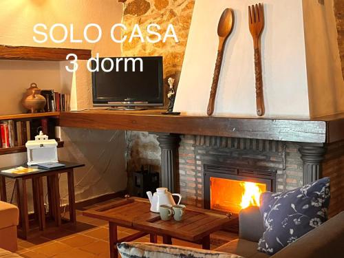 a living room with a fireplace and a tv at Casa rural Paraje de Yuste in Cuacos de Yuste