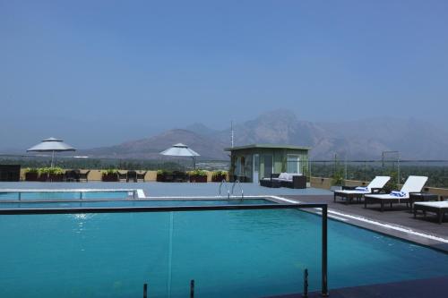 a large swimming pool with chairs and a table at Distrikt 9 in Palakkad