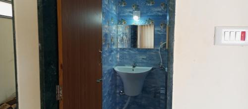 a blue tiled bathroom with a sink and a mirror at Dwarka Madhav Bunglow Only Family in Dwarka