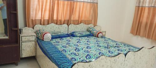 a bed with a blue and white comforter in a bedroom at Dwarka Madhav Bunglow Only Family in Dwarka
