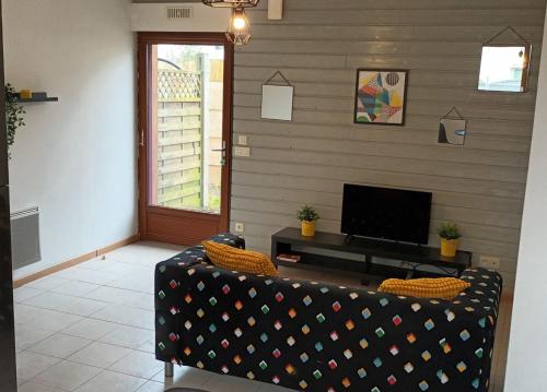 sala de estar con sofá y TV de pantalla plana en Chez Julien, en Bréal-sous-Montfort