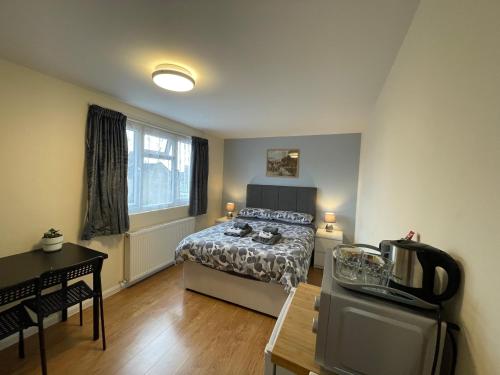 ein Schlafzimmer mit einem Bett und einem Tisch sowie eine Küche in der Unterkunft Kensal Lodge 2 Guest House in London