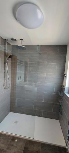 a bathroom with a shower with a large tile wall at High Tide in Braunton