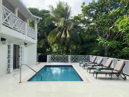 a swimming pool with lounge chairs next to a house at Gully Point in Saint James